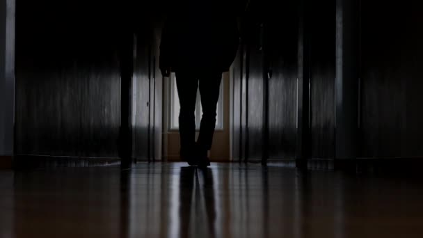 Un hombre camina por un pasillo oscuro. Ir pateando en la baldosa . — Vídeos de Stock