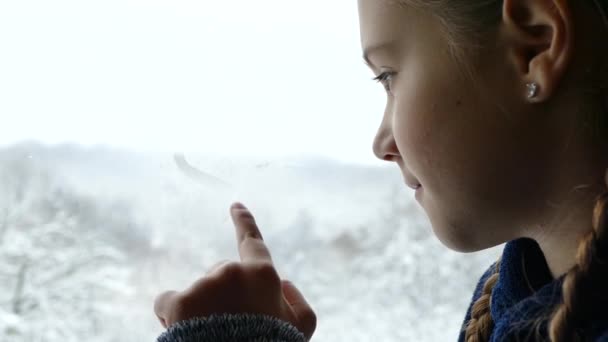 Chica Ventana Mira Bosque Cubierto Nieve Pintura Con Dedo Vidrio — Vídeo de stock