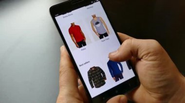 NEW YORK - 10 Aralık 2018: Akıllı telefondan online alışveriş. Elinde bir akıllı telefon ya da cihaz tut. İnternetten gömlek seç ve al. Mallar internetten alınıyor 