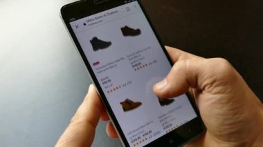 NEW YORK - 10 Aralık 2018: Akıllı telefondan online alışveriş. Elinde bir akıllı telefon ya da cihaz tut. İnternetten ayakkabı seç ve al. Mallar internetten alınıyor