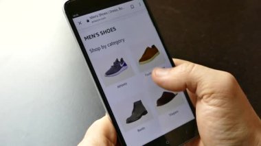 NEW YORK - 10 Aralık 2018: Akıllı telefondan online alışveriş. Elinde bir akıllı telefon ya da cihaz tut. İnternetten ayakkabı seç ve al. Mallar internetten alınıyor