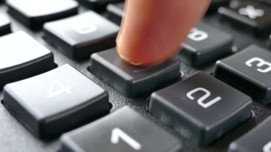 Parmaklar hesap makinesindeki tuşlara basıyor. Hesap makinesine güven. Numaralar düğmelere çizilmiş. Muhasebe ve iş geliri.