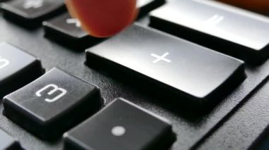 Parmaklar hesap makinesindeki tuşlara basıyor. Hesap makinesine güven. Numaralar düğmelere çizilmiş. Muhasebe ve iş geliri.