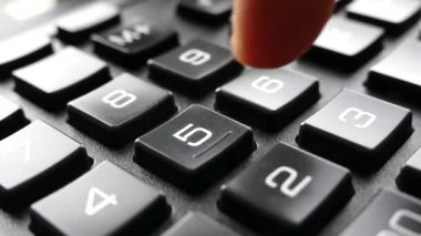 Parmaklar hesap makinesindeki tuşlara basıyor. Hesap makinesine güven. Numaralar düğmelere çizilmiş. Muhasebe ve iş geliri.