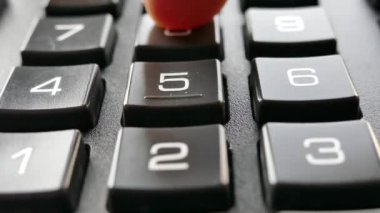 Parmaklar hesap makinesindeki tuşlara basıyor. Hesap makinesine güven. Numaralar düğmelere çizilmiş. Muhasebe ve iş geliri.