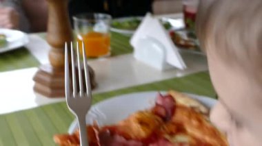 Çocuklar pizzacıda pizza yer ve meyve suyu içerler. Aileyle rahat bir kafede akşam yemeği. Kız meyve suyu içip gülümsüyor..  