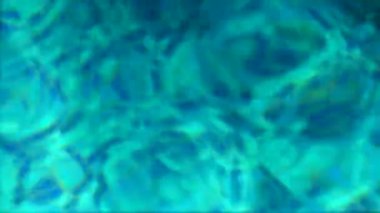 Su dokusu. Mavi havuzun berrak sularındaki güneş ışınlarının yansıması..