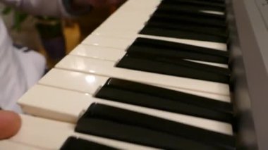 Piyano çalan bir adam. Bir müzik aletinin tuşlarına basmak için parmaklarını kullan. Bir sentezleyicide müzik oluştur.
