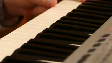 Piyano çalan bir adam. Bir müzik aletinin tuşlarına basmak için parmaklarını kullan. Bir sentezleyicide müzik oluştur.
