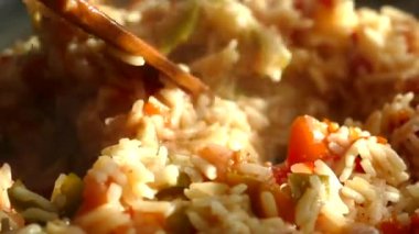 Büyük bir tavada pilav hazırla. Bir tabak pirinç ve sebze. Buhar sıcak bir öğle yemeğinden geliyor. Ev mutfağı. Pilaf ahşap bir spatulayla karıştırılır..