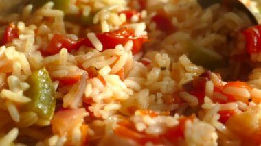 Büyük bir tavada pilav hazırla. Bir tabak pirinç ve sebze. Buhar sıcak bir öğle yemeğinden geliyor. Ev mutfağı. Pilaf ahşap bir spatulayla karıştırılır..