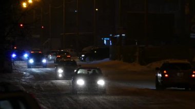Karlı yollarda gece şehir trafiği. Kışın gece yollarında arabaların farları parlar.