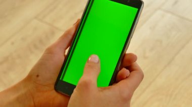 Akıllı telefon onların elinde tutulur ve onu kullanır. Yeşil arkaplanda yeşil ekran var. Kız aletimizin sayfalarını karıştırıyor. İnternetten alışveriş. Akıllı telefondan alışveriş yapmak. Krom