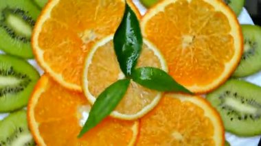 Tropikal meyve bir plaka üzerinde. Dilimlenmiş kivi portakal limon. Meyve siyah arka plan üzerine kapatın. Doğadan vitaminler.