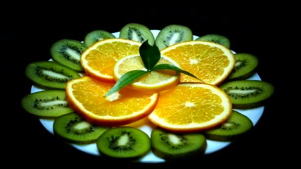 Trópusi gyümölcsök egy tányérra. Szeletelt kiwi narancs citrom. Gyümölcs közelről, a fekete háttér. Vitaminok, természet.