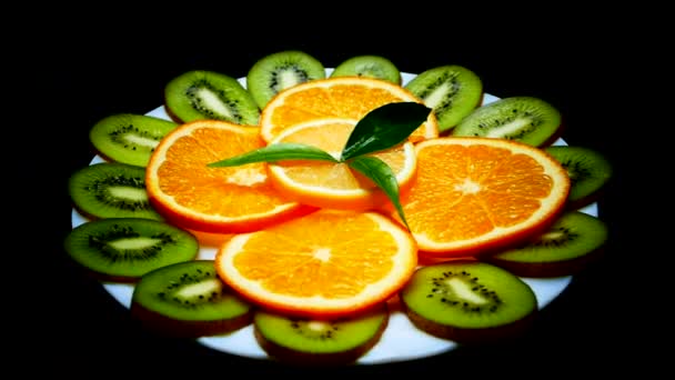 Frutos tropicais em um prato. Limão de laranja kiwi fatiado. Fruta de perto no fundo preto. Vitaminas da natureza . — Vídeo de Stock