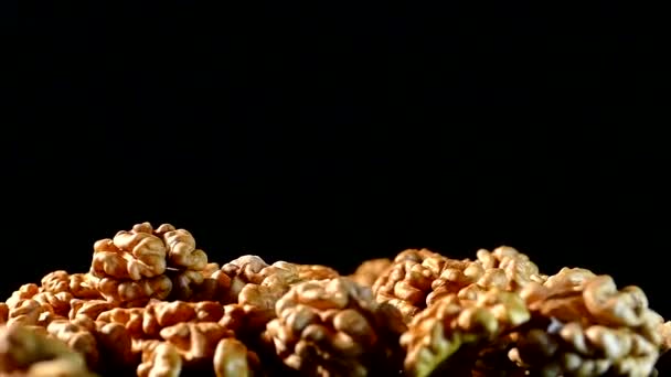 Closeup de noz. Nozes sem casca em um fundo preto. Kernels espalhados sobre a mesa . — Vídeo de Stock