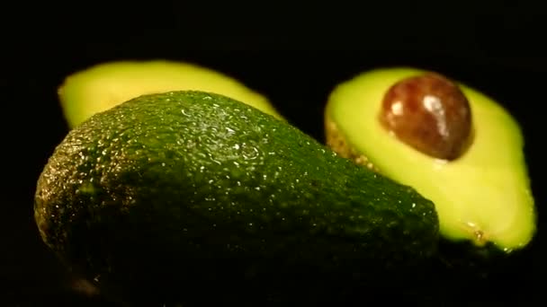 Abacate de fruto maduro em um fundo preto. Comida saudável e saudável. Casca verde, polpa amarela e porca grande . — Vídeo de Stock