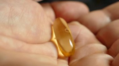 Avucunuza Omega 3 vitamini döküldü. Vitamini elinde tut. Açık sarı kapsüldeki doğal Omega 3 'ü kabul et. Sağlıklı bir yaşam tarzı. Doktor ilacı yazdı..