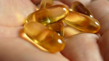 Omega 3 vitaminleri avuçlarına döküldü. Vitaminleri elinde tut. Açık sarı kapsüllerde doğal Omega 3 'ü kabul edin. Sağlıklı bir yaşam tarzı. Doktor ilaçları yazdı..