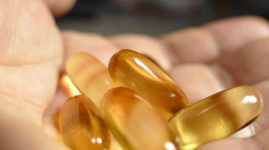 Omega 3 vitaminleri avuçlarına döküldü. Vitaminleri elinde tut. Açık sarı kapsüllerde doğal Omega 3 'ü kabul edin. Sağlıklı bir yaşam tarzı. Doktor ilaçları yazdı..