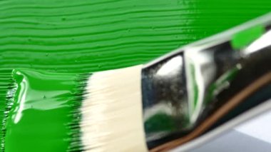 Sanat fırçasının yakın görüntüsü tuvali yeşil renge boyuyor. Yeşil arkaplan. 
