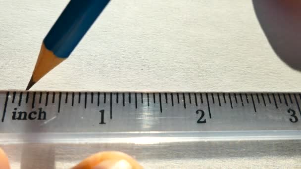 Teken een lijn in potlood onder de liniaal. Liniaal met inches close-up. Tekeningen tekenen. — Stockvideo