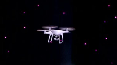 Siyah arka planda konser salonunda bir dron uçuyor. Quadrocopter yakın plan.