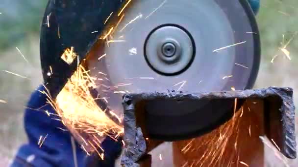 앵글 그라인더의 커팅 휠이 있는 금속 절단. 분쇄기에서 불꽃이 날아오게 됩니다. 작업자는 금속 구조를 구축합니다. 클로즈업. — 비디오