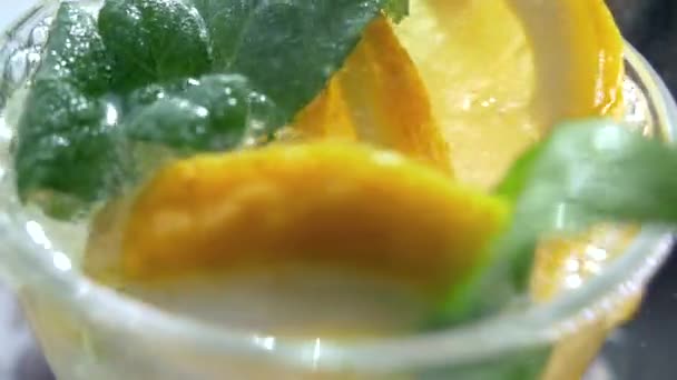 一杯清爽的软饮料 莫吉托被倒入一个玻璃特写 柠檬薄荷和闪烁着冰块的水 — 图库视频影像