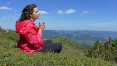 Dağların tepesindeki kız dinleniyor ve bir kupadan su içiyor. Şu güzel manzaraya bak. Dağlar, bulutlar ve orman. Yaz mevsimdir ve güzel havadır. Huzur içinde yat..