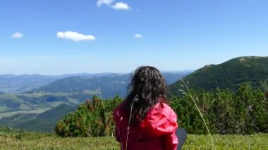 Dağların tepesindeki kız dinleniyor ve bir kupadan su içiyor. Şu güzel manzaraya bak. Dağlar, bulutlar ve orman. Yaz mevsimdir ve güzel havadır. Huzur içinde yat..