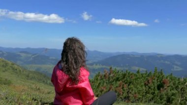Dağların tepesindeki kız dinleniyor ve bir kupadan su içiyor. Şu güzel manzaraya bak. Dağlar, bulutlar ve orman. Yaz mevsimdir ve güzel havadır. Huzur içinde yat..