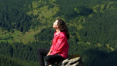 Kız dağın tepesinde oturur ve meditasyon yapar. Doğada rahatla. Mutluluk ve sükunet