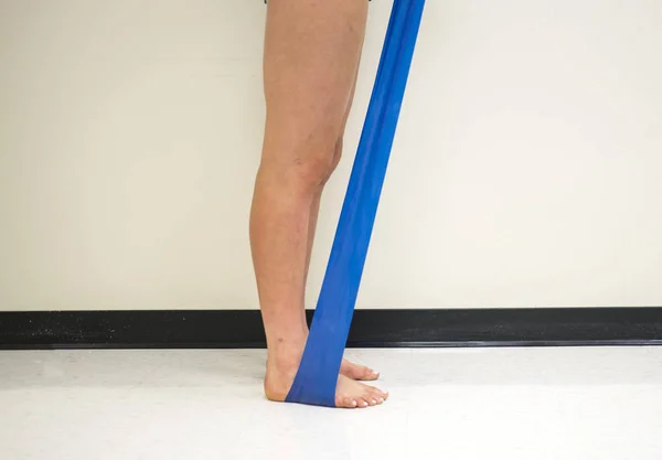 Standing female pulling up on a resistance band underneath her feet