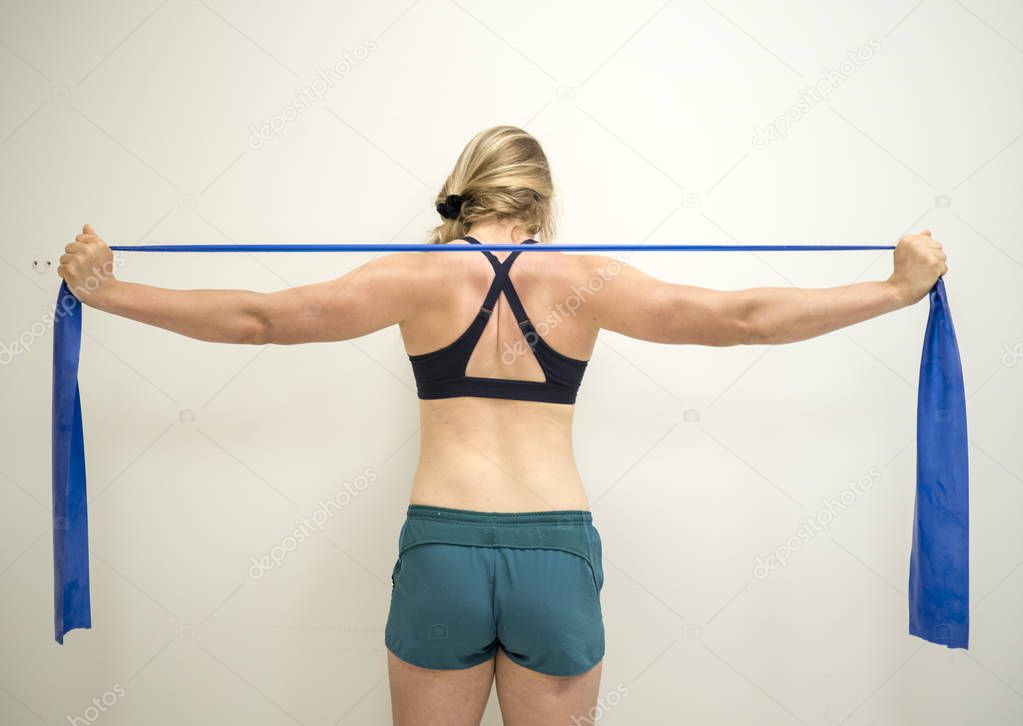 Strong female athlete using a resistance theraband to strengthen her arms muscles