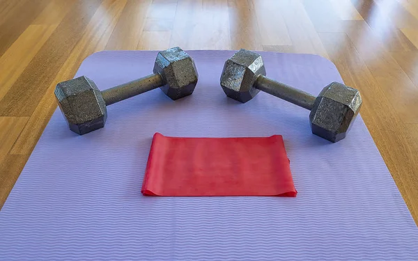 Dumbbells and Exercise band on a Yoga Mat for a Home workout