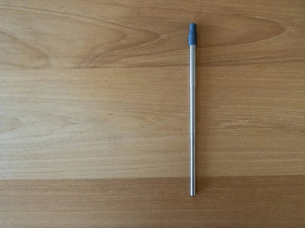 Environmentally friendly  large sized stainless steel metal reusable straw on a hardwood background version 2