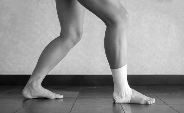 Black and white version of Athlete doing a calf stretch with an ankle tape job