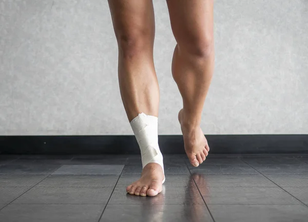 足首テープの仕事で回復足首捻挫のバランスをとるアスリート — ストック写真