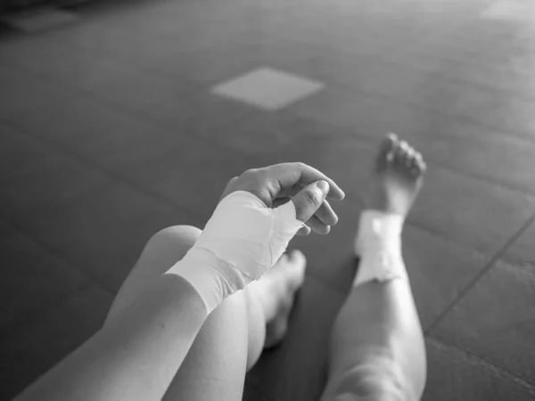 Black and white version of The injured athlete- athlete with thumb and ankle injuries and tape jobs