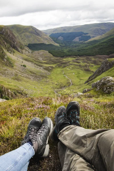 Bir çift oturan İskoçya peyzaj üzerinde bakan bir tepe üzerinde bacaklar