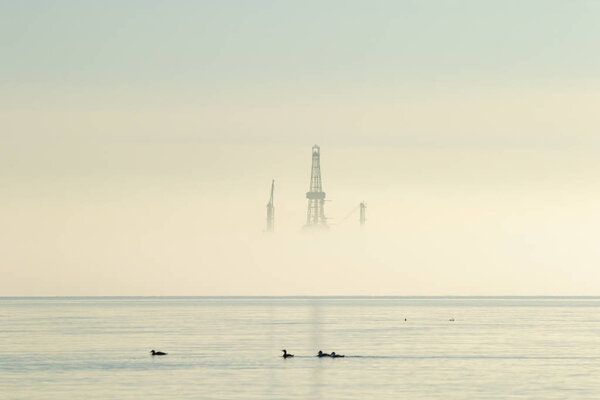 Oil platform rig covered in mist with birds in the sea Firth of Forth Scotland