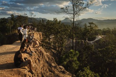 Tourists sitting down enjoying the view at Pai Canyon, Thailand clipart