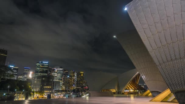 夜でタイムラプス ビデオ中心の壮大な都市景観のシドニー オペラ ハウスと明るい街の明かりに照らされた雲の移動 — ストック動画