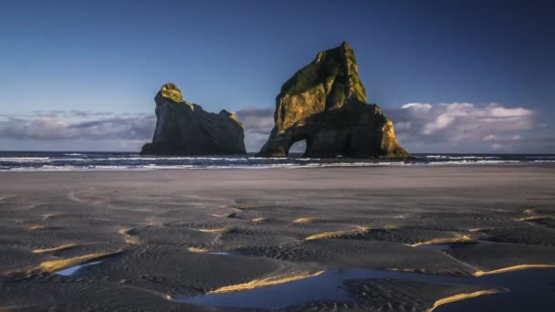 晴れた日にニュージーランドの空のビーチで自然なアーチを持つ壮大な岩 Wharariki ビーチ ケープ フェアウェル タイムラプス ビデオ — ストック動画