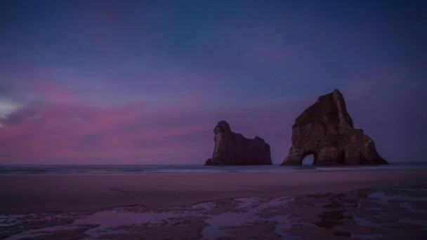 沖に巨大な岩の自然のアーチと美しい空のビーチで夜のタイムラプス ビデオ Wharariki ビーチ ニュージーランド — ストック動画