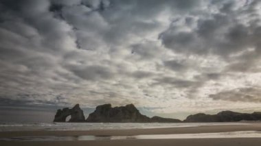 Muhteşem doğa güzel Wharariki Beach Yeni Zelanda kıyı kayalarda doğal kemer ile yukarıda. Timelapse video.