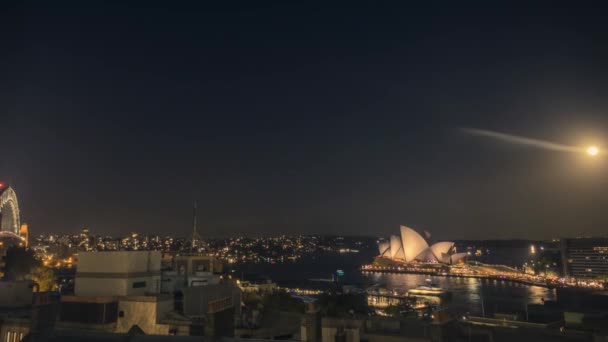晚上的悉尼 时光流逝在晴朗的夜晚与上升的月亮 灯火通明的悉尼歌剧院和悉尼海港大桥 — 图库视频影像