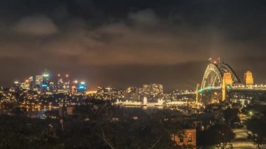Sydney Harbour Bridge ile Sydney cityscape ve ışıklı iş merkezi ve ofis binalarının ve gökdelenlerin muhteşem timelapse.
